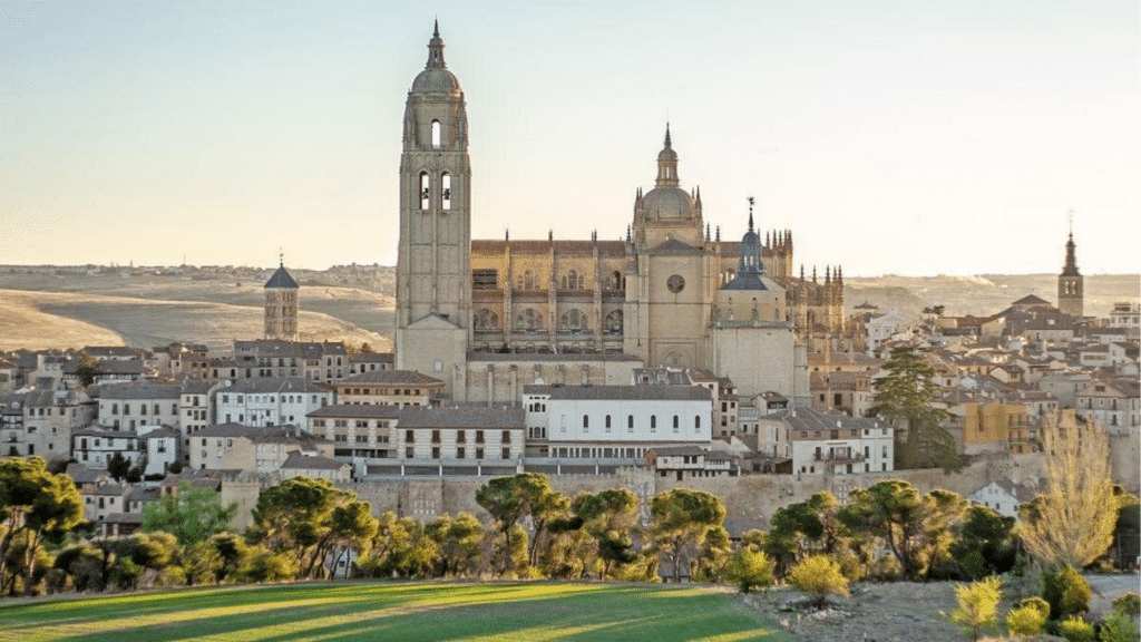 Segovia Cathedral towers above clustered rooftops and green countryside.