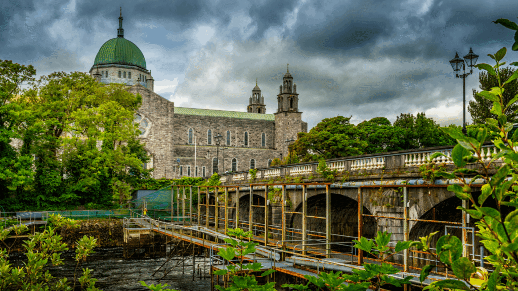 River Corrib flowing beneath a stone bridge with Galway city landmarks in the background